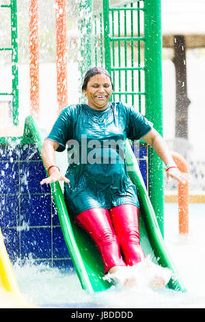 Happy 1 senior indiano donna ride di balneazione scorrevole nel parco acquatico Foto Stock