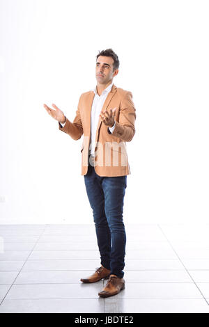 Un 35 - 40 anni uomo caucasico capelli scuri cool moderno look informale blazer, bracci mobili per spiegare lo sfondo bianco studio full shot Foto Stock