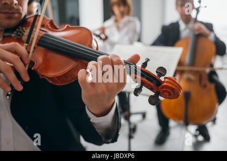 Il violinista di eseguire sul palco con musica classica Symphony Orchestra e con le mani vicino, il fuoco selettivo irriconoscibile persone Foto Stock