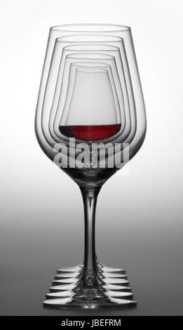 Alcuni bicchieri di vino in piedi consecutivi in una fila nel gradiente dorso grigio, uno parzialmente riempito con un bicchiere di vino rosso Foto Stock
