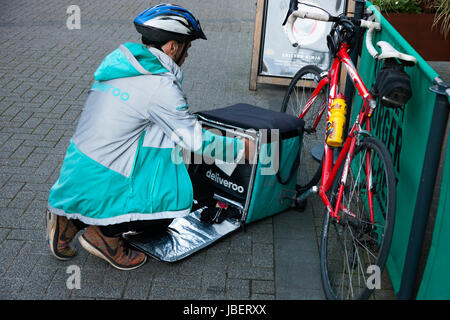 Deliveroo cibo da asporto corriere consegna ciclo pedale / spingere bike ciclista facendo una consegna eseguiti in Royal Leamington Spa. U.K. (88) Foto Stock