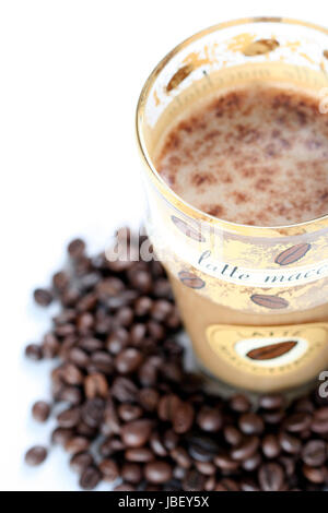 Latte Macchiato in vetro sulla costa di caffè in grani Foto Stock