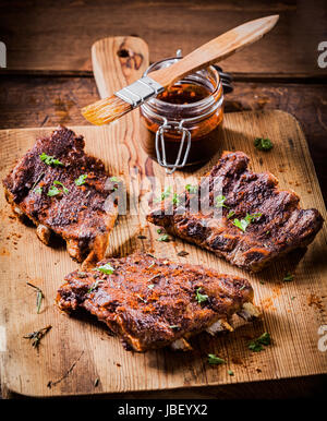 Tre porzioni di piccante grigliate di nervature imbastite con una saporita salsa aromatica e guarnita con erbe per un delizioso pasto Foto Stock