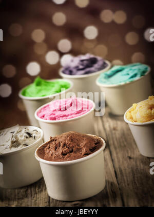 Delizioso assortimento di parte del gelato in singoli vasetti di plastica in più colori e sapori con un frizzante bokeh di luci festive Foto Stock