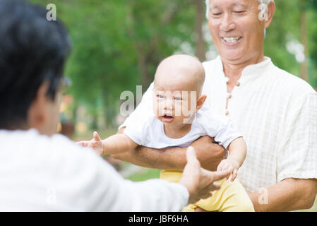 Asian nonni giocando con il bambino nipote al giardino esterno. Foto Stock