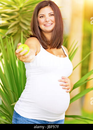 Ritratto di Allegro femmine gravide di offrire fresco verde mela, passeggiate nel parco esotico, vacanze estive, mangiare sano per pregnants, nuovo concetto di vita Foto Stock