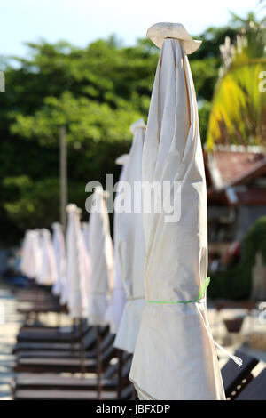 Ombrelloni in piedi in fila sulla spiaggia Foto Stock