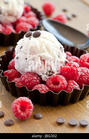 Eis mit Himbeeren und Schokolade auf rustikalem Holz Foto Stock