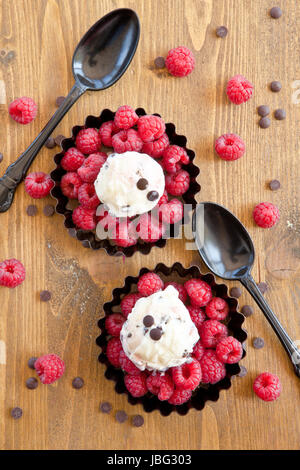 Eis mit Himbeeren und Schokolade auf rustikalem Holz Foto Stock