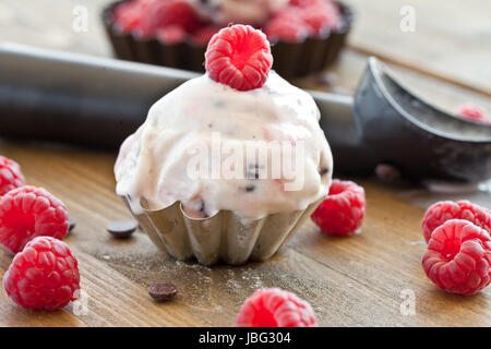 Eis mit Himbeeren und Schokolade auf rustikalem Holz Foto Stock