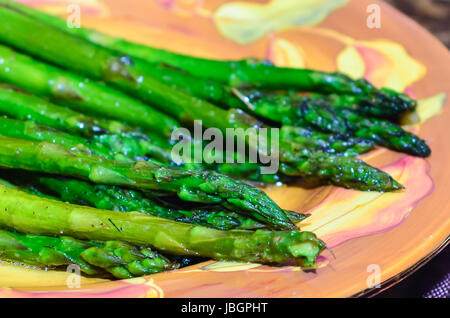 Saltate Asparagi organico con erbe e aglio su piastra Foto Stock