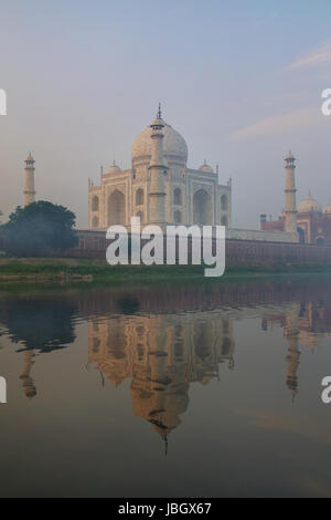 Vista del Taj Mahal con nebbia mattutina si riflette nel fiume Yamuna, Agra, Uttar Pradesh, India. Taj Mahal è stato designato come un patrimonio mondiale dell'UNESCO si Foto Stock