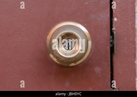 La manopola dello sportello e la serratura in ottone sulla vecchia porta di legno Foto Stock
