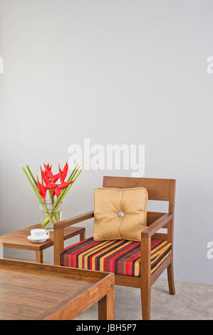 Beige colore rosso striped sedia imbottita con tavolino e fiori Foto Stock