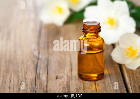 Jasmin olio essenziale con fiori di gelsomino sul tavolo di legno dello sfondo. Trattamento di bellezza. Spazio di copia Foto Stock
