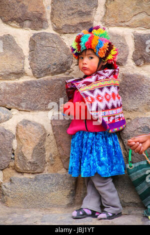 Ragazza locale in piedi vicino a Fortezza inca di Ollantaytambo, Perù. Ollantaytambo è stato il royal station wagon di Imperatore Pachacuti che conquistarono la regione. Foto Stock