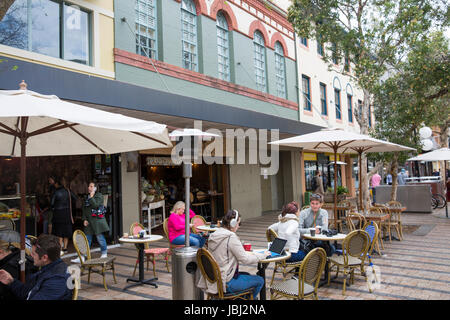 Signora donna che indossa le cuffie lavorando sul suo computer portatile presso un ristorante e caffetteria cafe in Manly Beach,Sydney , Australia Foto Stock