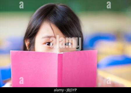 Ragazza utilizza un libro per coprire il suo volto Foto Stock