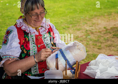 PIESTANY, Slovacchia - 20 Maggio 2017: una donna non identificato, vestito in costumi folk, rende la bobina tradizionale lacci in un modo tradizionale durante le arti Foto Stock