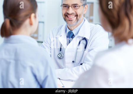 Fiducioso praticante parlando a pazienti in ospedale Foto Stock