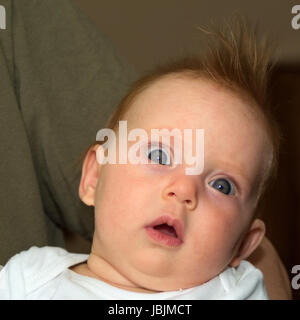 Quasi un bambino di quattro mesi con molto aperto gli occhi guardando nella telecamera Foto Stock