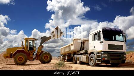 Caricatore a estremità anteriore posizionando la pietra e la sabbia in un grande camion o rimorchio Foto Stock