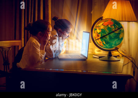 Le ragazze che guardano con stupore al laptop di notte Foto Stock