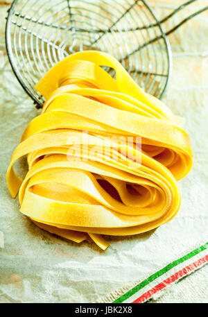 Cuocere le fettuccine pasta italiana giacente su un vecchio filo succhieruola di cucina durante la preparazione e la cottura di un traditioal pasto mediterraneo Foto Stock