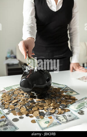 Primo piano della donna inserendo dollar nel maiale salvadanaio Foto Stock