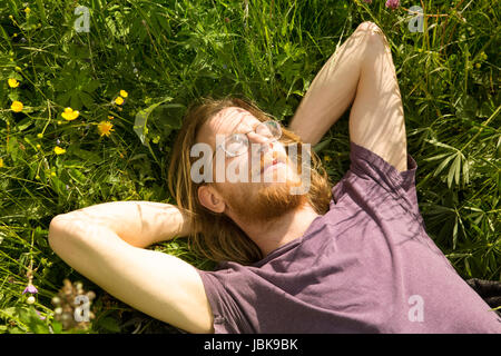 I giovani i capelli rossi uomo disteso in erba e dorme Foto Stock