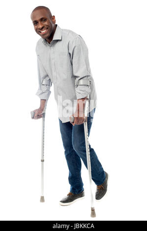 Uomo sorridente con le stampelle cercando di camminare Foto Stock