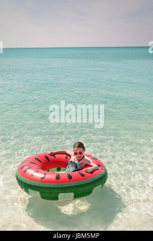 Ritratto ragazza galleggianti in anguria anello gonfiabile nella soleggiata tropicale oceano blu Foto Stock