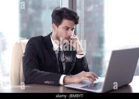Imprenditore occupato in ufficio a lavorare sul suo computer portatile. Foto Stock