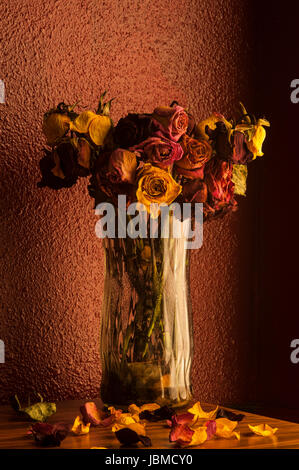 Rose multicolori avvizzimento in vaso di vetro con finestra calda luce della finestra Foto Stock