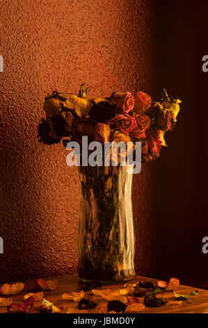 Rose multicolori avvizzimento in vaso di vetro con finestra calda luce della finestra Foto Stock