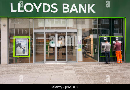 Due uomini che usano macchine cashpoint fuori dalla Lloyds Bank su Tottenham Court Road, Londra, Inghilterra, Regno Unito Foto Stock
