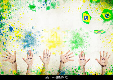 Il tifo mani, pallone da calcio e i colori della bandiera Brasile Foto Stock