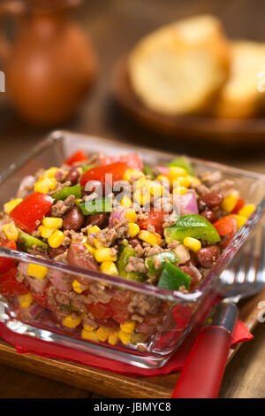 Chili con carne Insalata di carne macinata, fagioli rossi, il peperone verde, il pomodoro, il mais dolce e le cipolle rosse servite nella ciotola di vetro (fuoco selettivo, la messa a fuoco di un terzo nell'insalata) Foto Stock