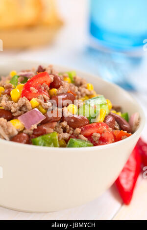 Chili con carne Insalata di carne macinata, fagioli rossi, il peperone verde, il pomodoro, il mais dolce e le cipolle rosse servite nella ciotola con il peperoncino sul lato (fuoco selettivo, la messa a fuoco al centro dell'insalata) Foto Stock