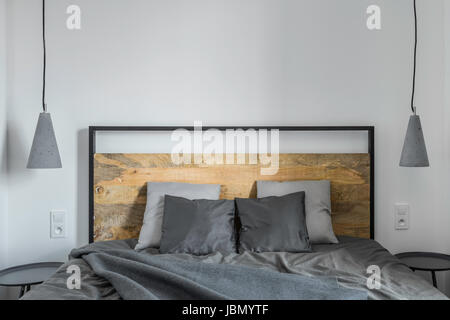 White camera da letto con letto in legno, lampade e biancheria di colore grigio Foto Stock