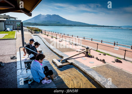 Gruppo di persone la balneazione i loro piedi nelle acque di origine vulcanica di Kyushu Foto Stock