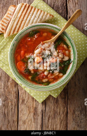 Zuppa di pomodoro con fagioli, spinaci e parmigiano vicino sul tavolo. vista verticale da sopra Foto Stock