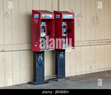 Abbandonato a gettone telefoni pubblici a pagamento con moneta slot release, i graffiti sulla parete e telefoni. . Foto Stock