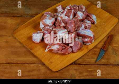 Piccoli pezzi di grezzo a base di carne di manzo con coltello su un scheda di cucina. Foto Stock