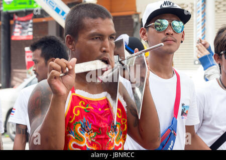 Uomo con le guance trafitto da elemento di ancoraggio in un corteo durante i nove imperatore dèi Festival (festival vegetariano) in Phuket, Tailandia Foto Stock