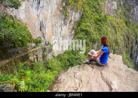 Giovane donna godendo la vista del Ponte di Inca e cliff percorso nei pressi di Machu Picchu in Perù. Il ponte è una parte di un sentiero di montagna che capi ad ovest di M Foto Stock