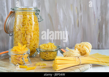 Assortimento di pasta in vasi pm tavolo in legno Foto Stock