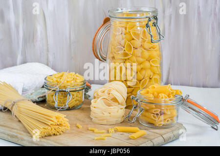 Assortimento di pasta in vasi pm tavolo in legno Foto Stock