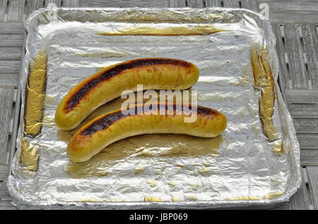 Salsicce alla griglia sulla griglia con la lamina d'argento, close up, macro, frame completo Foto Stock