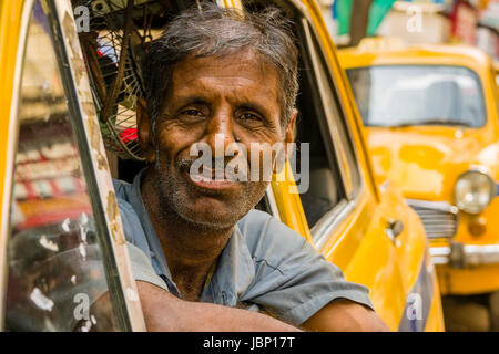 Un taxi driver all'interno di un taxi giallo, cabina, è in attesa per i clienti Foto Stock